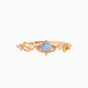 Macro detail of gold Saturn ring with light blue opal and sparkling side crystals