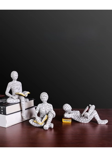 Set di tre figurine da lettura nordiche in resina su una scrivania in legno scuro e nero