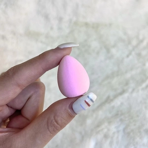 Close-up of pink mini tear-drop makeup sponge held by fingers for precise application