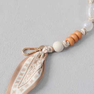 Close-up of beaded handbag chain strap with silk scarf decoration and metal clasp