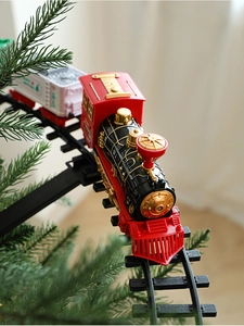 Electric Christmas train with red engine and white carriages running around tree track
