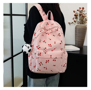 Detail of pink corduroy cherry print backpack with a cute panda plush charm on zipper