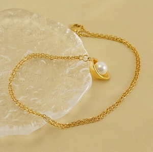 Detail of 18k gold plated double-chain necklace with shell pendant and pearl