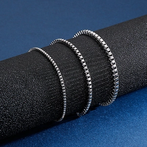Three sizes of silver titanium steel box chains on dark pedestals for jewelry display