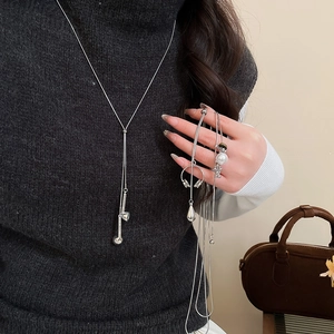 Silver long sweater chain necklace with pearl and bear charms on a black sweater