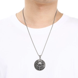 Macro shot of a vintage silver stag skull medallion pendant worn by a male model