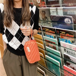 Gros plan d'un sac en toile vichy rouge et blanc tenu par un mannequin en décor chic