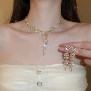 Détail macro d'un ensemble collier et boucles d'oreilles doré avec pompons et faux diamants