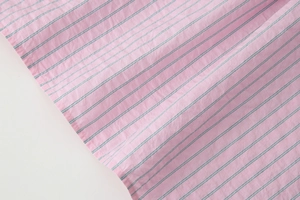 Gros plan sur un tissu en popeline rose à fines rayures sombres et texture tissée