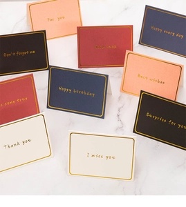 Flat lay of colorful minimalist greeting cards with gold foil text on marble background
