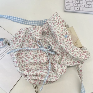 Detailed macro view of floral canvas bag with drawstring and blue checkered ribbon straps