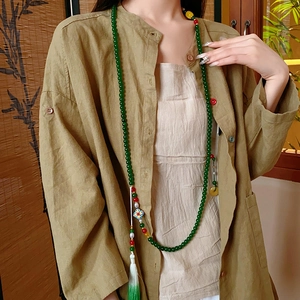 Détail d'un collier de perles vertes avec pendentif cloisonné et pompons