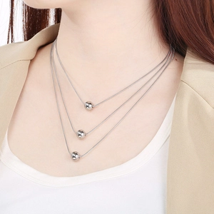 Close-up of triple-layered silver snake chain necklace with polished metal beads