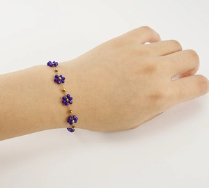 Close-up of bohemian 18K gold stainless steel bracelet with blue crystal flowers on wrist