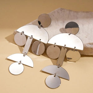 Dettaglio di orecchini geometrici in argento con piastre metalliche circolari e rettangolari