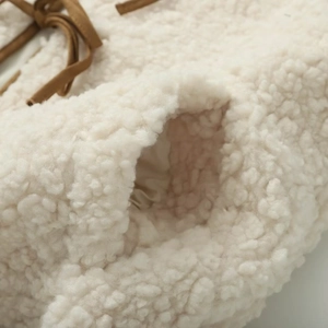 Detail of off-white sherpa fleece vest with brown drawstring and pocket texture