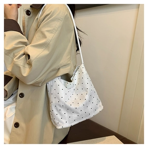Detailed side view of a white polka dot tote bag worn with a beige trench coat