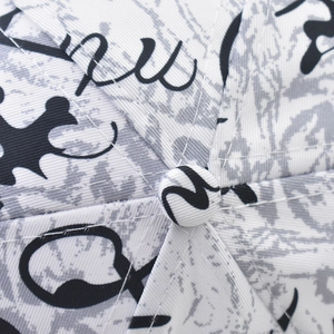 Close-up of baseball cap top showing cotton fabric texture with artistic graffiti print
