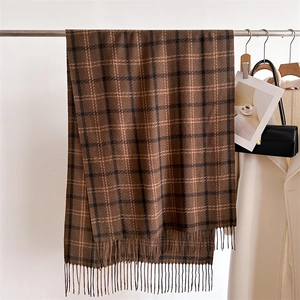 Detail of classic brown plaid scarf with fringe, hanging in a stylish autumn setting