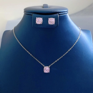 Detailed set of pink cushion-cut crystal necklace and earrings on a blue display stand