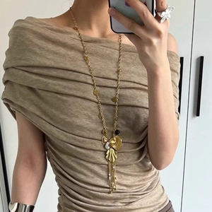 French vintage gold long necklace with leaf, heart and tassel pendants on a model