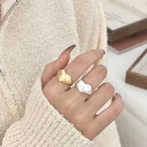 Hammered textured heart rings in silver and gold plating on hand with knit sweater