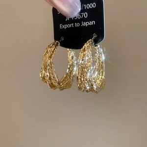 Macro shot of gold textured braided hoop earrings with intricate metallic weave details