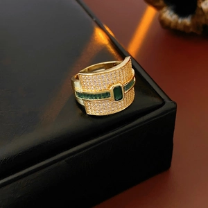 Macro detail of vintage gold-plated ring with emerald-cut green stones and pave crystals