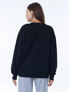 Detail showing the back view of a minimalist black oversized fleece crewneck sweatshirt