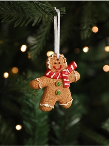 Detailed view of gingerbread man ornament hanging on a Christmas tree with festive bokeh
