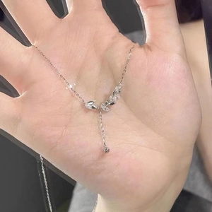 Macro shot of silver wheat pendant necklace with sparkling zircons held in hand
