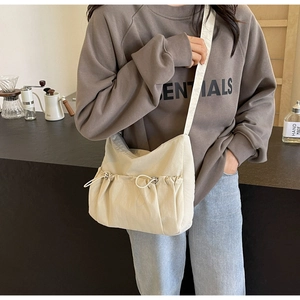 Detail of beige nylon crossbody bag featuring stylish drawstring pleats and a wide strap