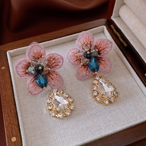 Detailed macro view of pink embroidered flower earrings with crystal teardrop pendants