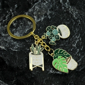 Golden succulent plant keychain with crazy plant lady enamel charms on a black rock surface