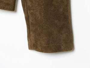 Gros plan sur la texture du daim synthétique marron et les coutures de la veste