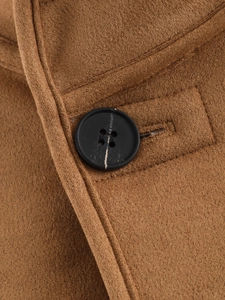 Macro detail of brown faux suede fabric texture with black four-hole button and stitching