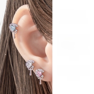 Macro detail of French vintage heart cartilage piercing with colorful zircon stones