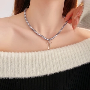 Détail du collier de perles grises avec pendentif noeud argenté porté par un mannequin