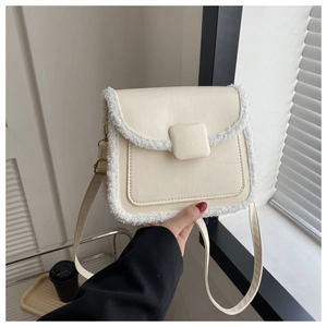 Detail of cream leather shoulder bag featuring plush white faux fur trim and square buckle