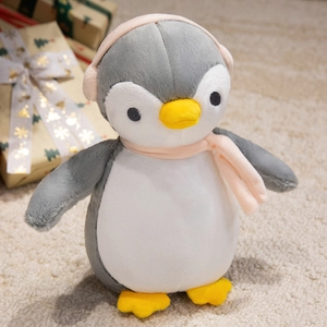 Close-up of cute stuffed penguin toy with pink scarf and earmuffs on festive background