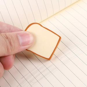 Close-up of toast-shaped eraser being held over a lined notebook for size display