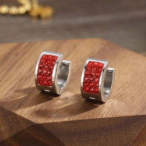 Macro detail of stainless steel huggie earrings featuring micro-pave red cubic zirconia