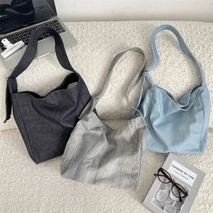 Three large tie-dye canvas tote bags in grey and blue on a soft white carpet background