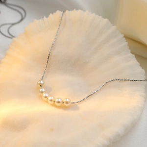 Macro shot of 18k titanium steel necklace featuring six gradient white pearls on shell