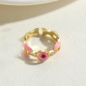 Detail of gold open ring featuring pink enamel devil eye and delicate diamond accents