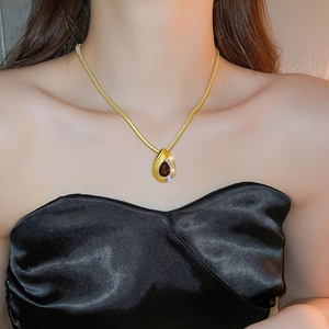 Detail of gold snake chain necklace with dark brown gemstone and diamond pendant