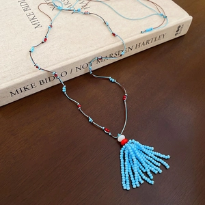 Dettaglio della collana etnica con nappe blu e perline di cocco su base in legno