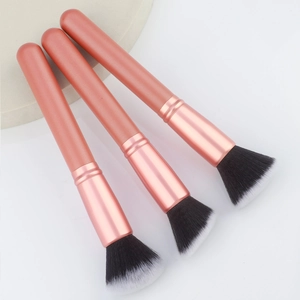 Detailed view of three rose gold flat-top foundation brushes with soft gradient bristles