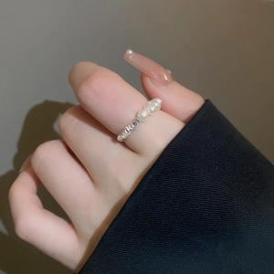 Détail d'une bague en argent texturée avec de petites perles blanches sur un mannequin