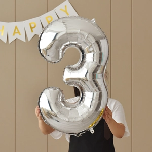 Detail of a large 40-inch silver number 3 foil balloon held for party decoration